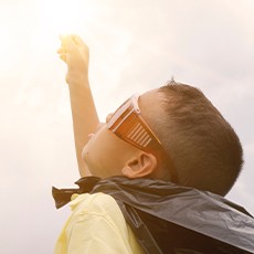 Young boy in cape looking at sun Young boy in cape looking at sun