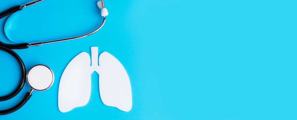 November Lung Cancer Awareness Month - get your lung screening. Image shows a sblue background. To the left is a loosely placed stethoscope. beside it, a white shape cut out to look like lungs. 